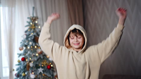boy in a hoodie near a christmas tree