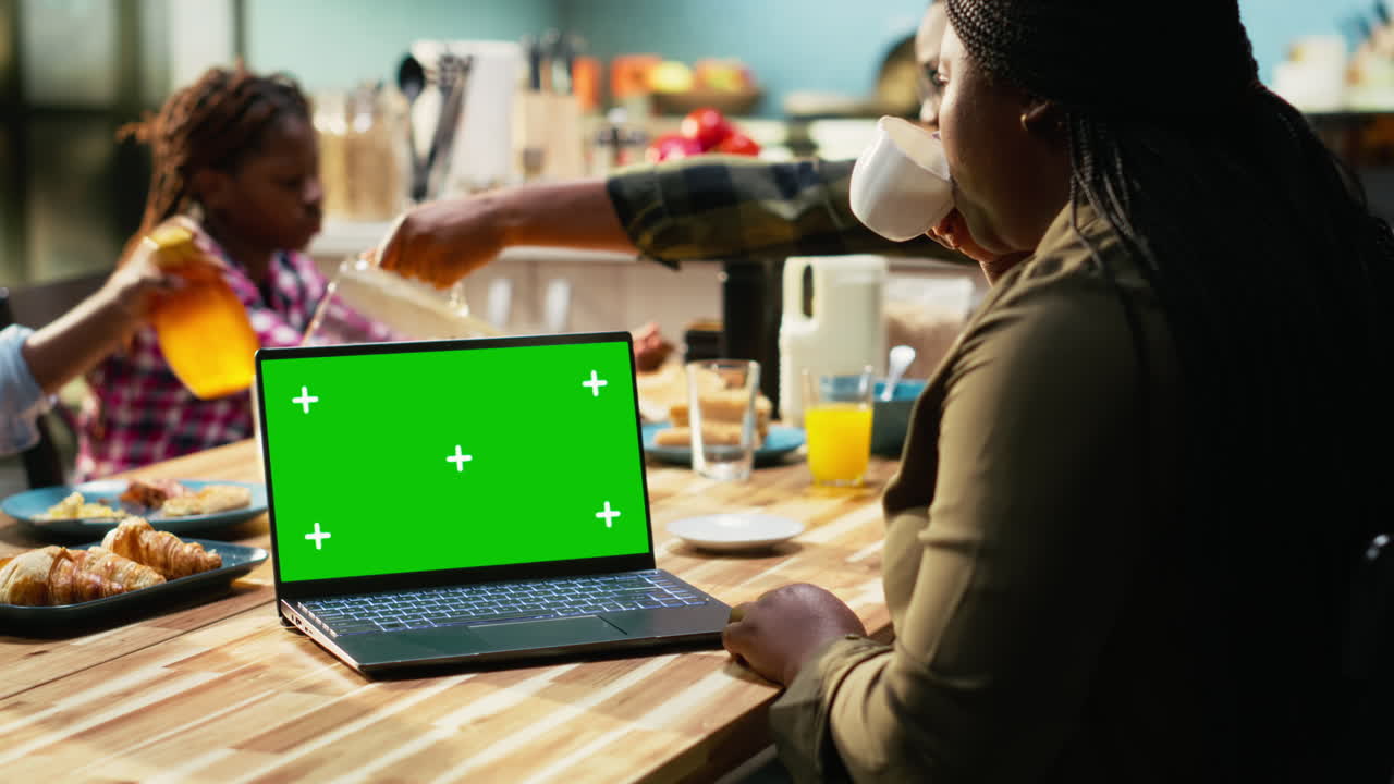Family having breakfast with a laptop showing a green screen