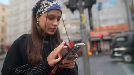young woman using phone on city street