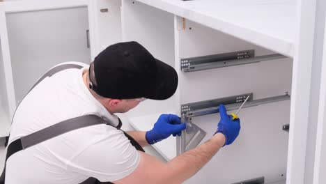 a man installs furniture in the kitchen with a screwdriver a man installs furniture in the kitchen with a screwdriver repair of accessories in the house the concept of home renovation