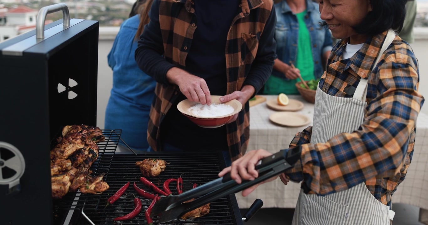 Happy Asian Woman Grilling Chicken and Peppers at an Outdoor Barbecue