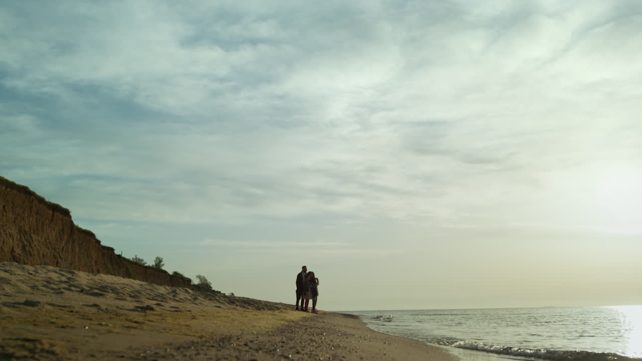 grupo de personas de pie en el paisaje de la playa. familia caminando al atardecer el mar por las olas se estrellan.