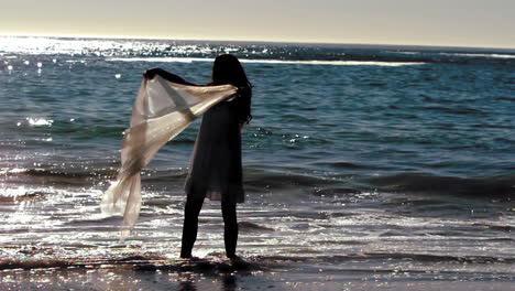 Silhouette-of-woman-holding-her-sarong-in-the-air