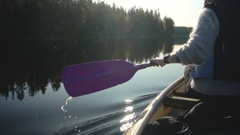 mujer remando en canoa en un hermoso lago en otoño, vista trasera cerrada a cámara lenta