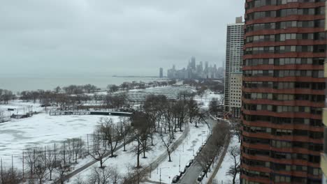drone passes apartment building to reveal downtown chicago on cold winter day