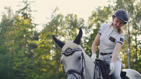 women is stroking her horse after walk in nature. horseback riding is an important hobby for her.