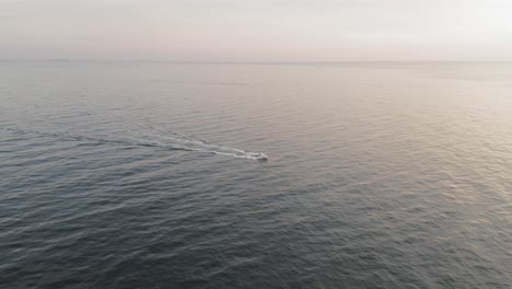 tilting down on a boat motoring across the sea during a winter sunrise off the coast of maine aerial