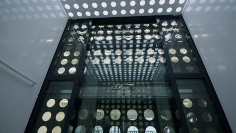 slowmotion low angle shot of inside elevator with circles pattern going dwon