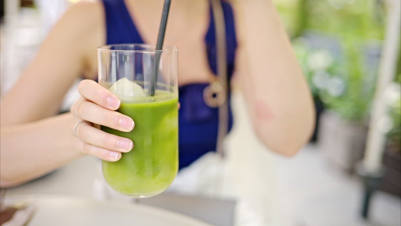 Primo piano al rallentatore di una donna che beve un cocktail matcha con ghiaccio