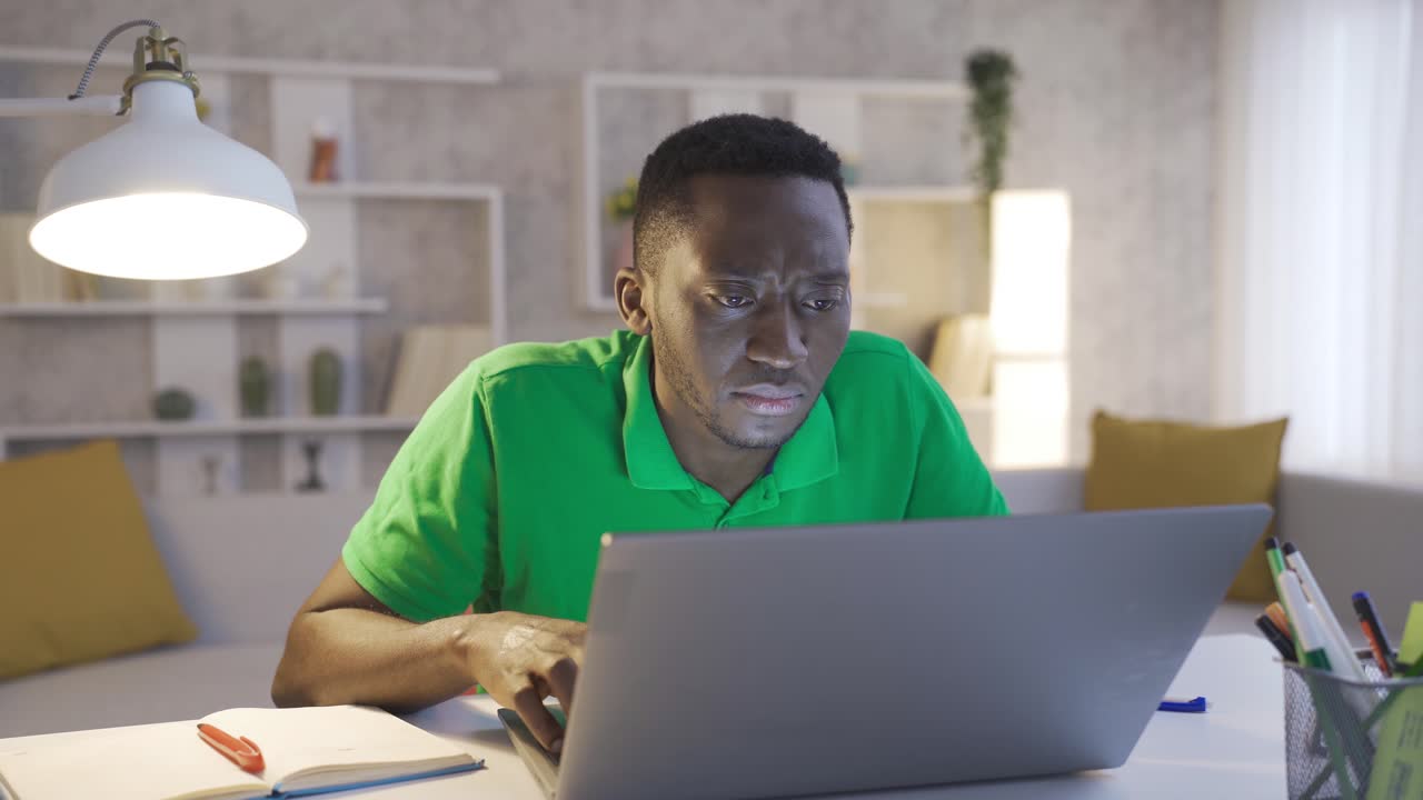 Shocked frustrated African young man worried, looking at computer screen, not feeling well.