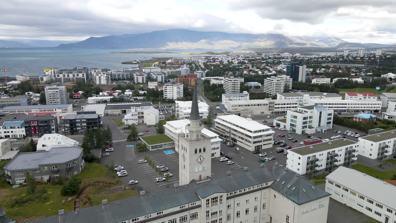 4K drone glide over Reykjavik's heart, with the grand bell tower standing sentinel, backed by the serene waterfront