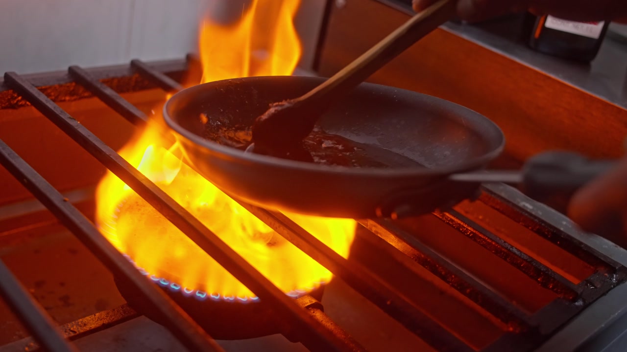 SLOW MOTION CLOSE UP SHOT OF A MEXICAN CHEF MAKING A FLAMBÉ SAUCE WITH MEZCAL