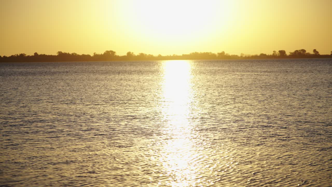 Golden Sunset Reflection on Calm Water with Distant Horizon
