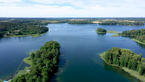 aerial: reveal shot of lake and isolated islands with growing trees on a bright summer day