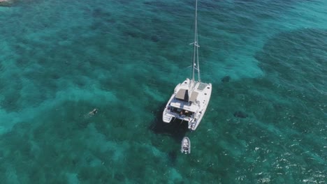 Aerial-Drone-View-of-Bahamas-Deserted-Island-with-Solitary-Sailboat-and-Snorkelers