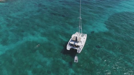 aerial drone view of bahamas deserted island with solitary sailboat and snorkelers