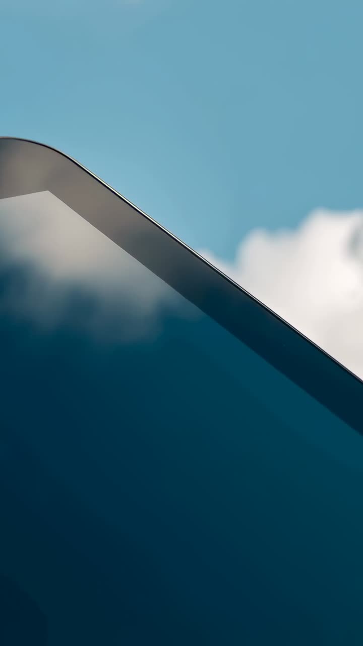 Video verticale: Prospettiva che si sposta mostrando l'angolo di un telefono che scorre sul cielo, con il vetro che riflette le nuvole per una pubblicità.