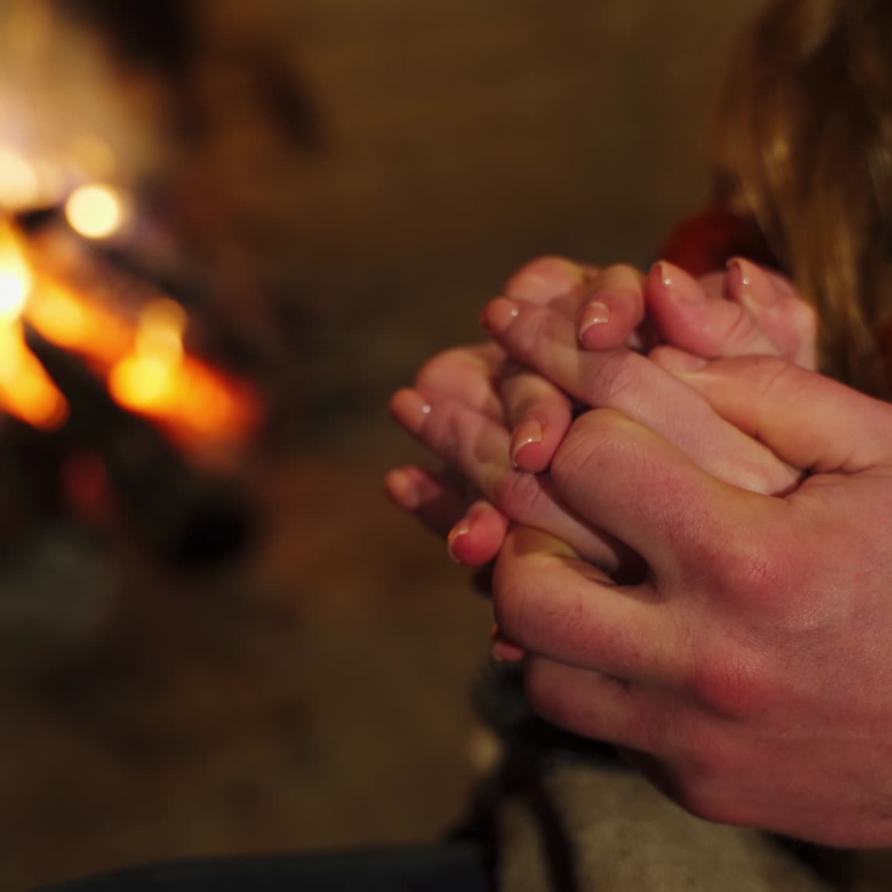Primo piano delle mani di una coppia che si toccano alla luce del falò. Amanti che si accarezzano durante il loro appuntamento. Amore e relazioni.