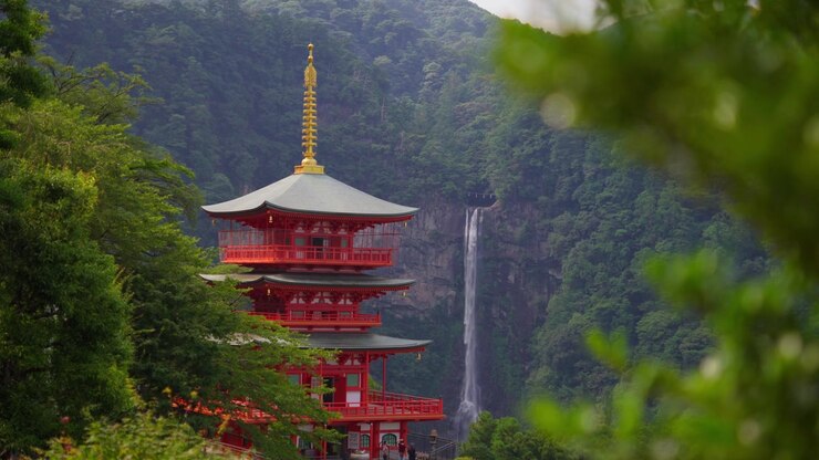 Le cascate di Nachi si ergono scenograficamente dietro la tradizionale pagoda rossa del tempio Seiganto-ji in questa tranquilla veduta di uno dei paesaggi culturali più iconici di Wakayama