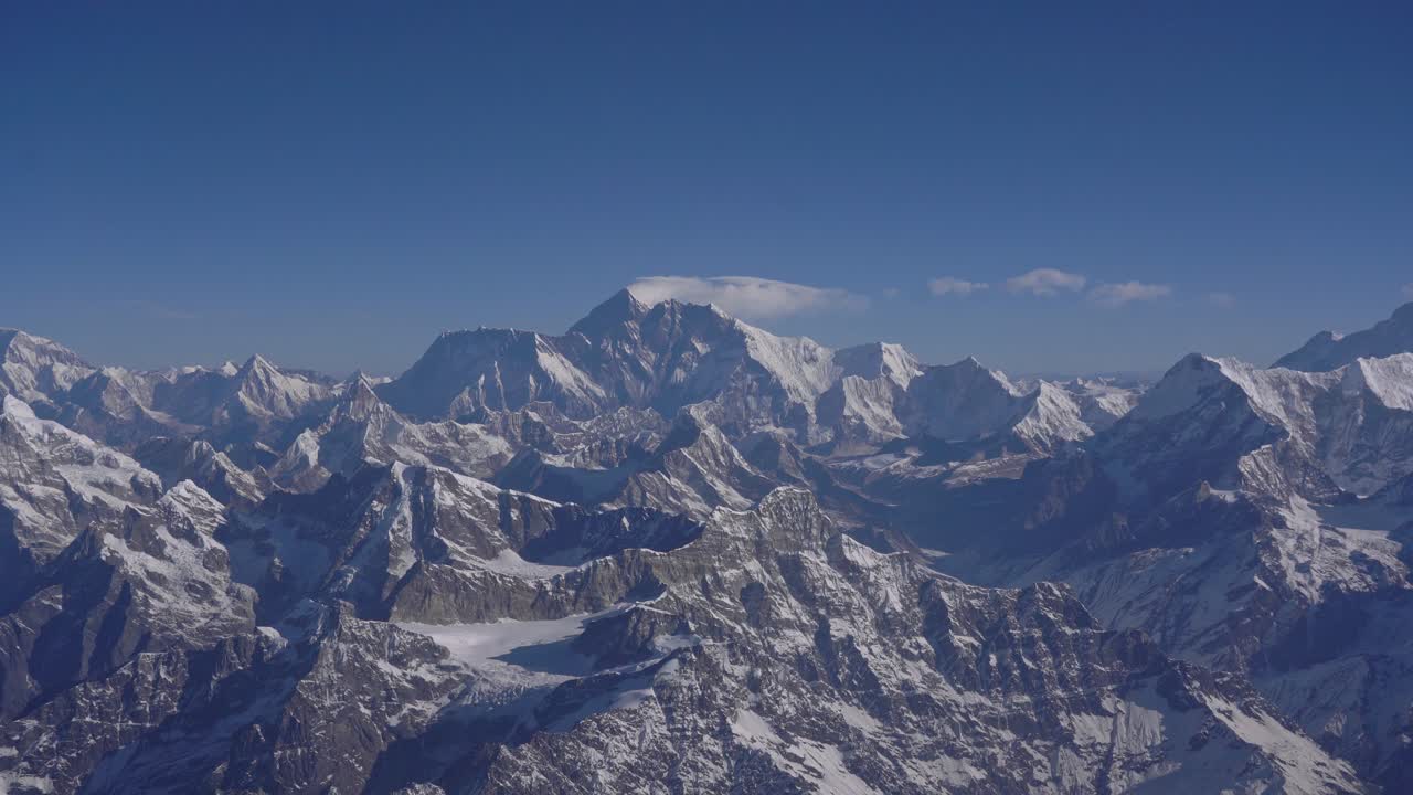 Footage of the Himalayan mountain range in Nepal from an aircraft window. Shows snow-capped peaks, clouds, and breathtaking natural scenery from high altitude