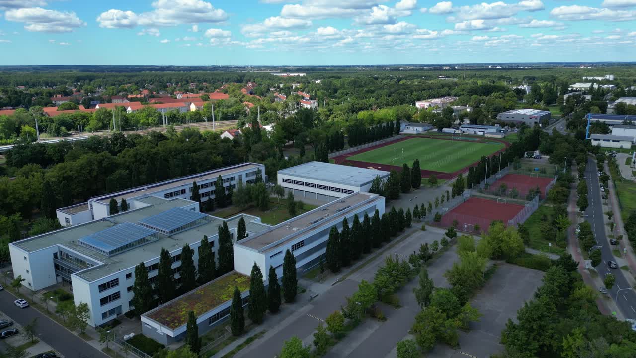 sports facilities at Hennigsdorf high school, including a soccer field, running track and other buildings in residential areas. Magic aerial view flight vertical bird's eye view drone