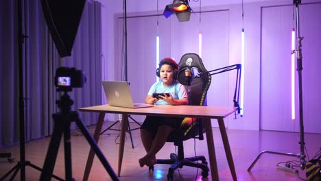 asian little boy holding mobile phone and talking to camera while live stream, professional light equipment
