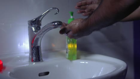 un hombre lavándose las manos con lavado a mano en un lavabo