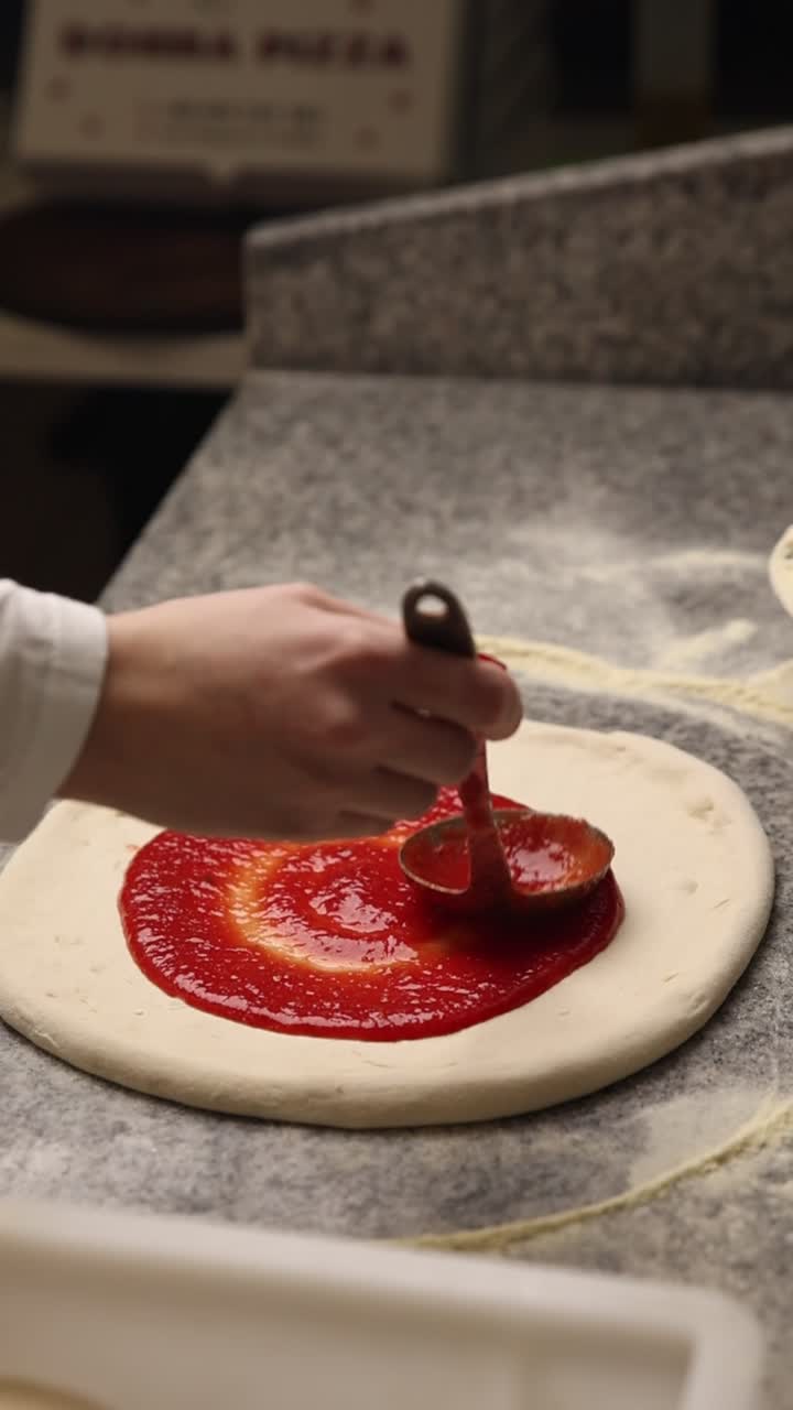 Spalmare la salsa di pomodoro sulla pasta fresca della pizza