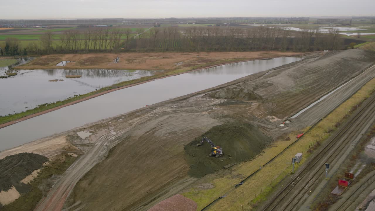 excavadora que prepara tierras para nuevas infraestructuras cerca de vías ferroviarias, aérea