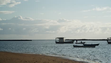 Pescador-En-La-Parte-Superior-De-Un-Bote-Lanzando-Redes-De-Pesca-Al-Agua-En-Cámara-Lenta-En-Un-Día-Soleado-Con-Botes-En-El-Horizonte