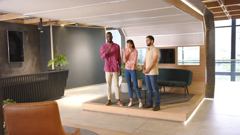 standing together, three diverse colleagues discussing work in modern office space