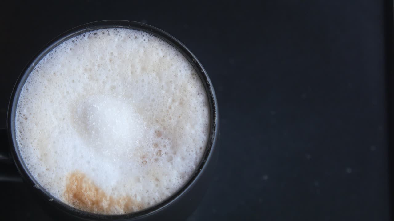 으로 검은 컵에 캐푸치노를 담은 근접 촬영입니다.