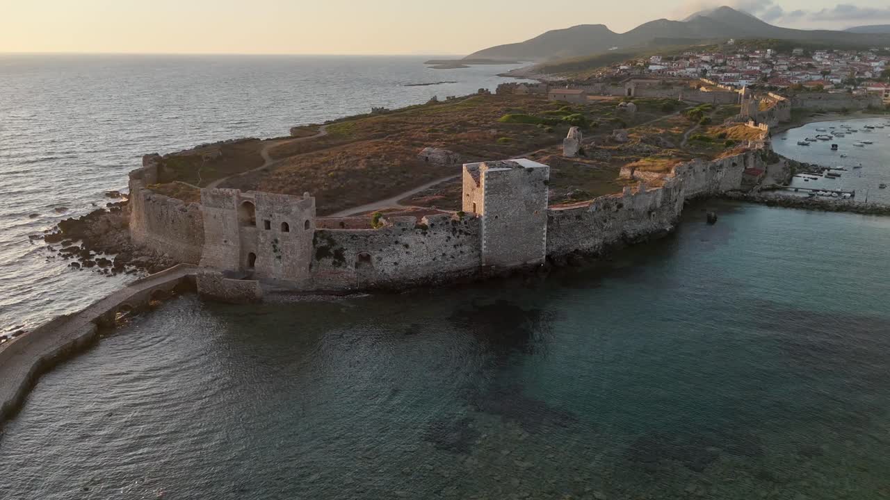 Methoni,Messenia,Peloponnese,Aerial view backwards from Methoni Castle surrounded by crystal clear waters,than pan right towards town. Background are hills and beautiful landscape during golden hour