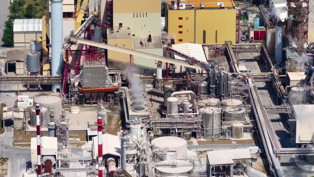 Industrial pulp and paper mill aerial view showing large tanks, pipelines, and smokestacks. Cellulose production and bioenergy facility