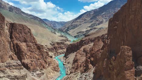 aerial drone shot of a crystal-clear blue river meandering near a quiet monastery in a remote valley.