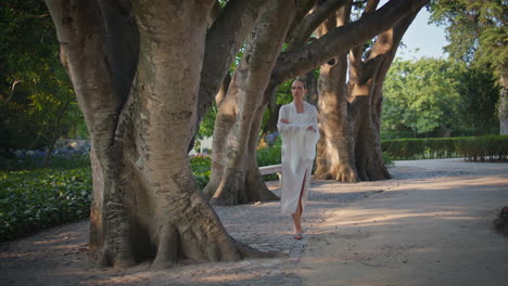 dreamy lady walking park alley wrapped in white scarf. serene woman strolling