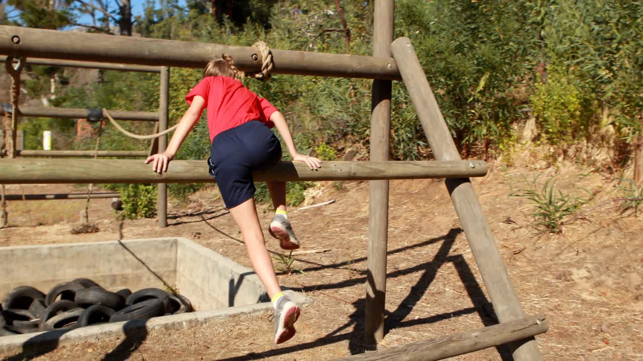 niña haciendo ejercicio en equipos al aire libre durante una carrera de obstáculos