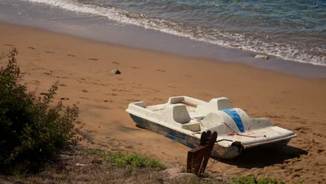 a colorful paddle boat rests on the sandy beach, ready for a day of fun on the water. the calm waves and bright sun create the perfect backdrop for this relaxing seaside activity.