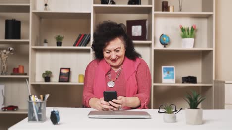anciana juega un juego móvil en un teléfono inteligente con entusiasmo y una sonrisa
