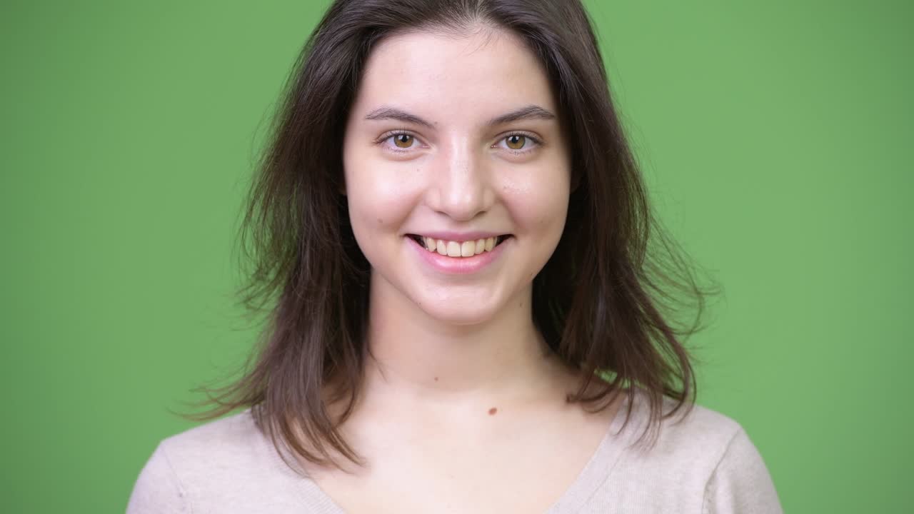 joven feliz mujer hermosa sonriendo contra un fondo verde