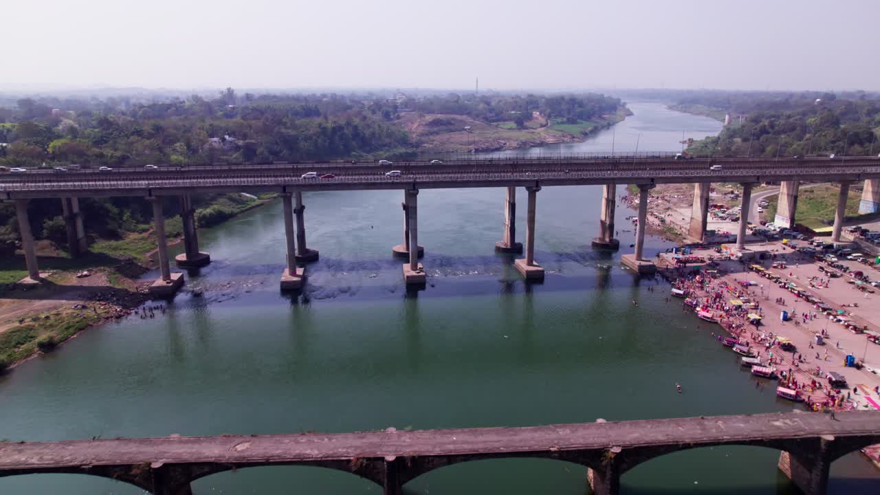 Tilwara Narmada River Bridge with flying birds and boats at narmada ghat, tilwara, jabalpur, madhya pradesh, india. day time, push in, tilt down, drone shot, 4k.