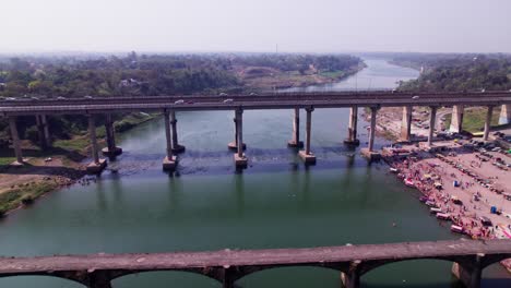 tilwara narmada river bridge with flying birds and boats at narmada ghat, tilwara, jabalpur, madhya pradesh, india. day time, push in, tilt down, drone shot, 4k.
