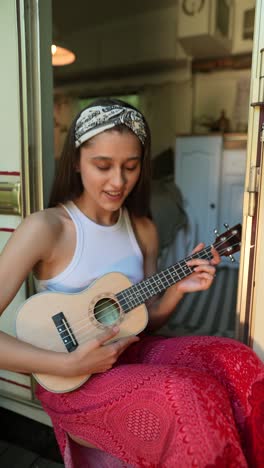 young woman playing ukulele in a camper van