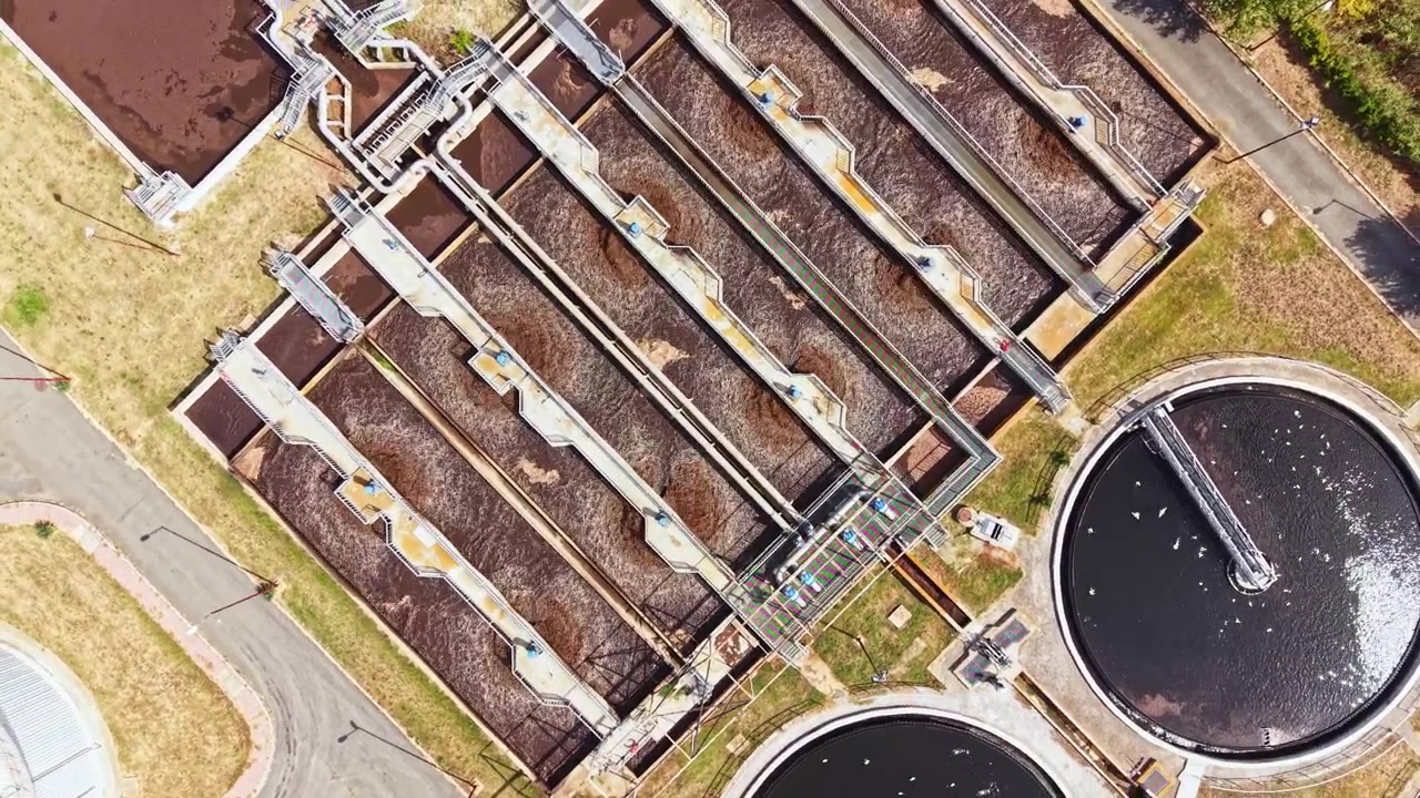 Wastewater treatment facility in operation showing multiple treatment tanks and processes during daylight hours