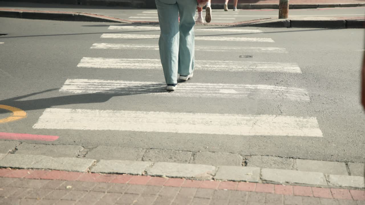 Des personnes traversent le passage piéton, tandis qu'un cycliste descend de son vélo et le pousse.