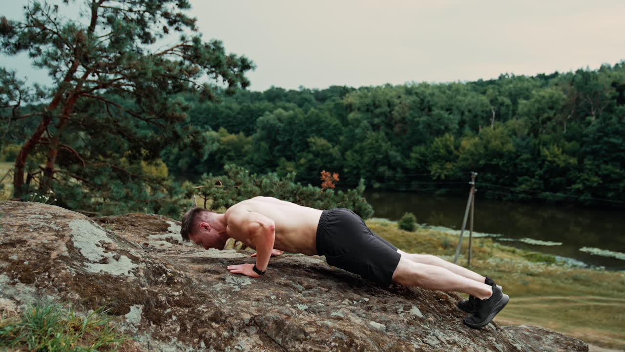 Sportsman doing pushups on the big rock. Exercising, work out and healthy lifestyle in the nature.