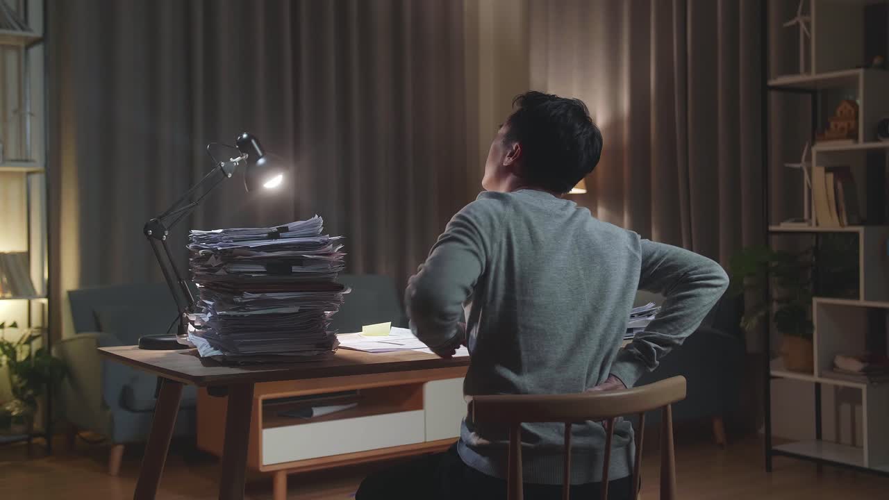 집 에서 문서 를 열심히 작업 하는 동안 허리 통증 을 겪는 아시아인 의 뒷면