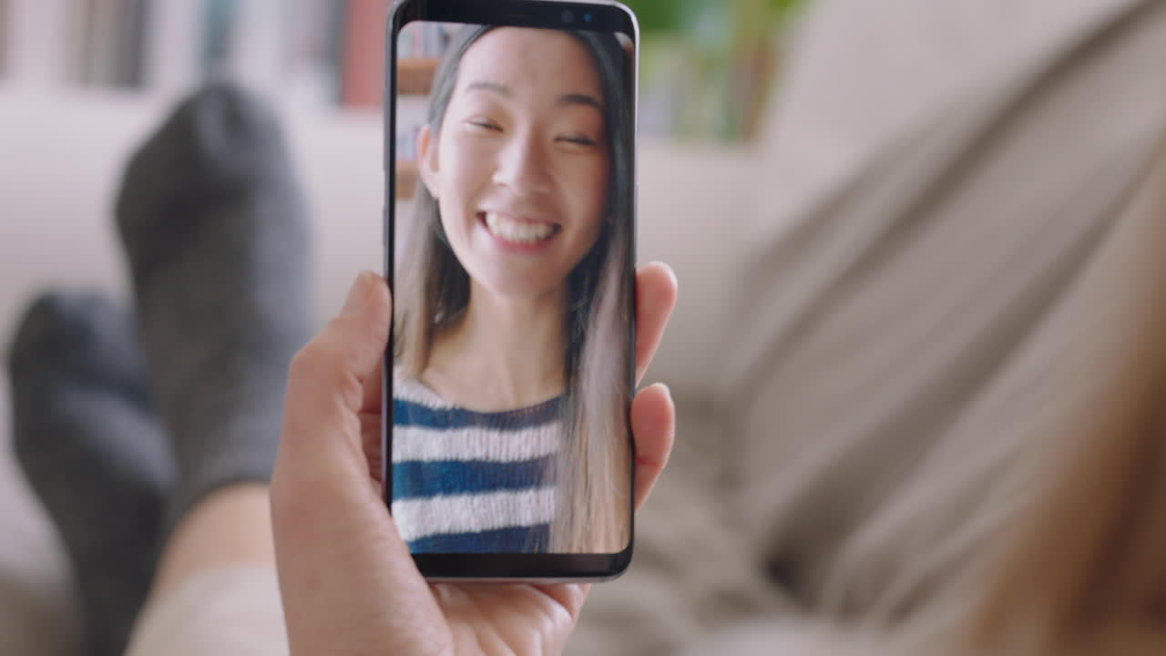 mujer joven teniendo video chat usando teléfono inteligente en casa hablando con un amigo disfrutando de la conversación compartiendo estilo de vida en el teléfono móvil orientación vertical 4k metraje