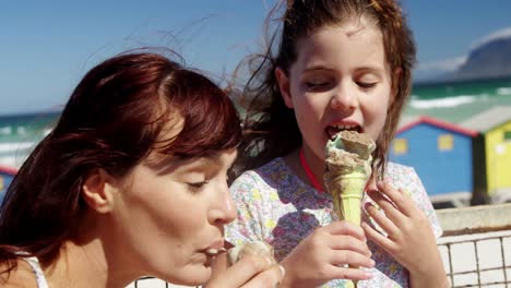 mother and daughter having ice cream at beach