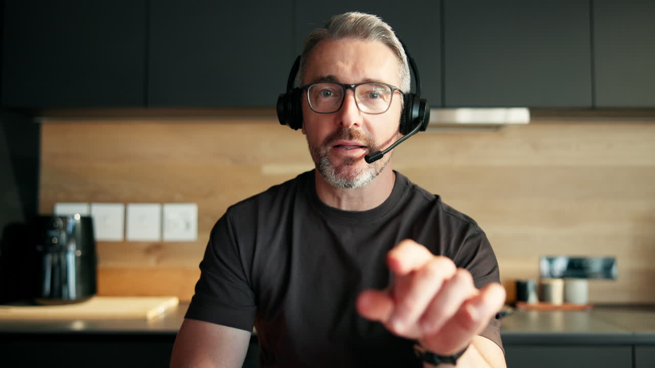 Uomo maturo con cuffie che parla durante una videochiamata